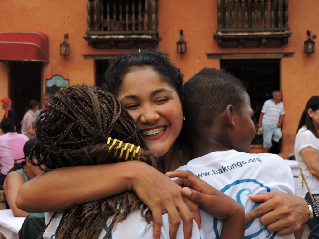 Una joven abraza a dos niños con una gran sonrisa